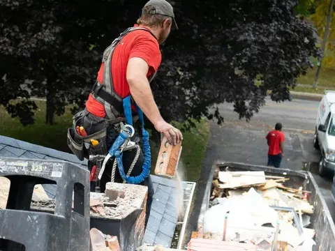 Operario retirando escombro de una chimenea a un contenedor de obra